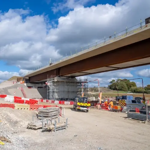 HS2 construction site showing a bridge structure, scaffolding and site access road under a cloudy sky